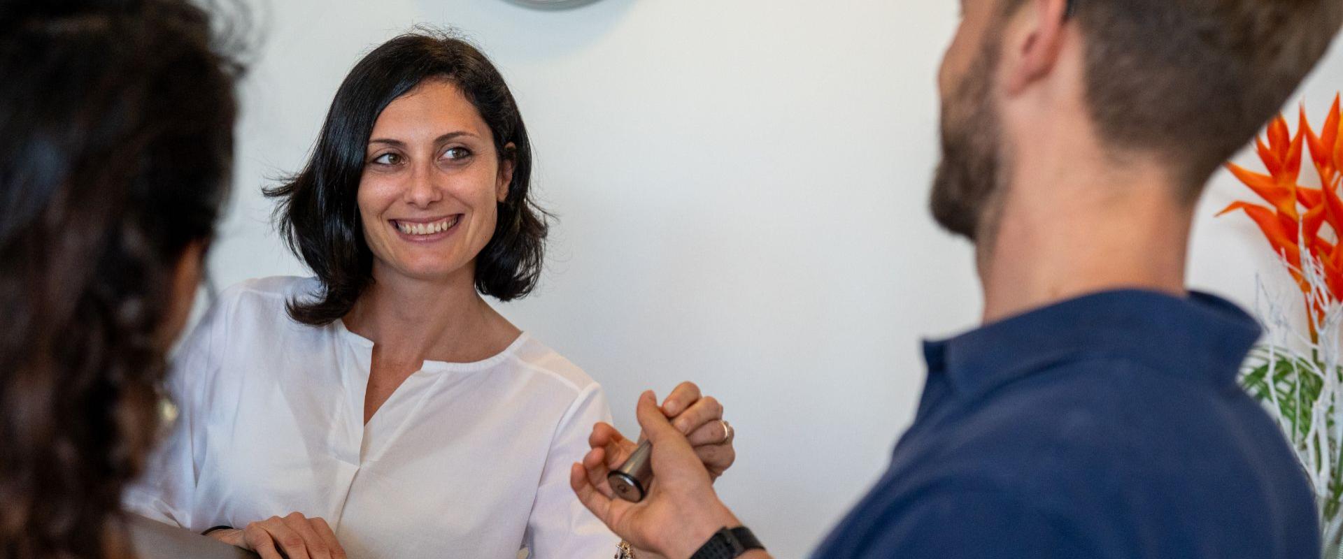 Woman at counter receives keys from smiling man.
