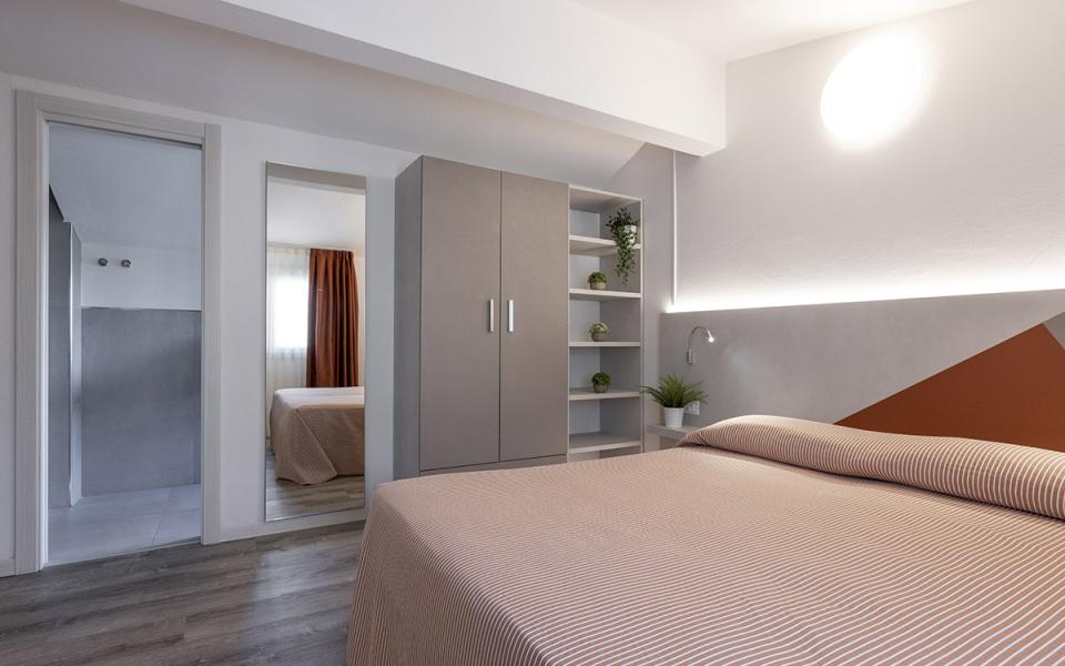 Camera moderna con letto matrimoniale, armadio, ripiani e illuminazione soffusa.