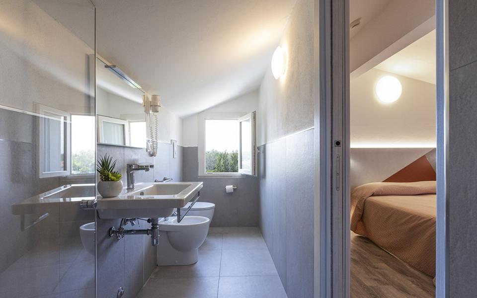Bagno moderno con lavabo, bidet e vista su camera da letto accogliente.