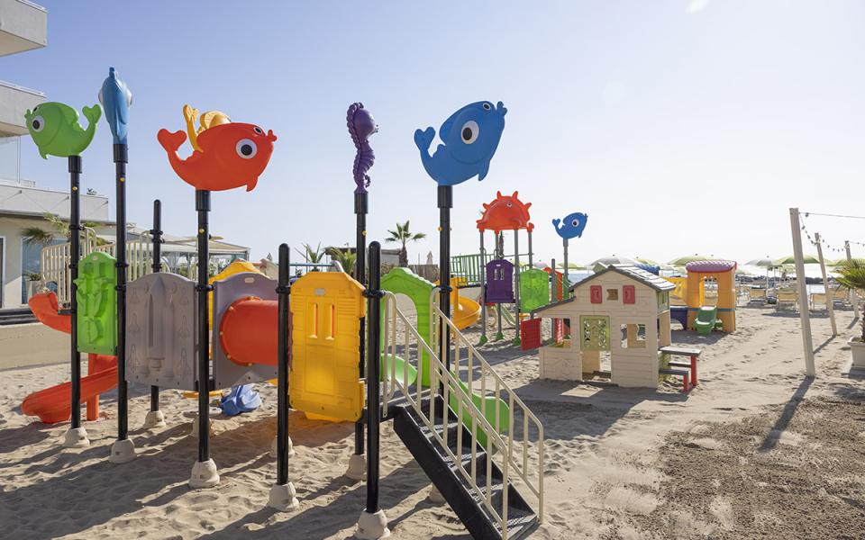 Parco giochi sulla spiaggia con scivoli colorati e giochi a tema marino.